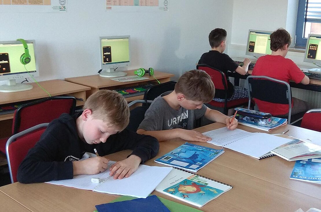 Kinder arbeiten am PC und im LOS-Lehrmaterial im LOS Wuppertal